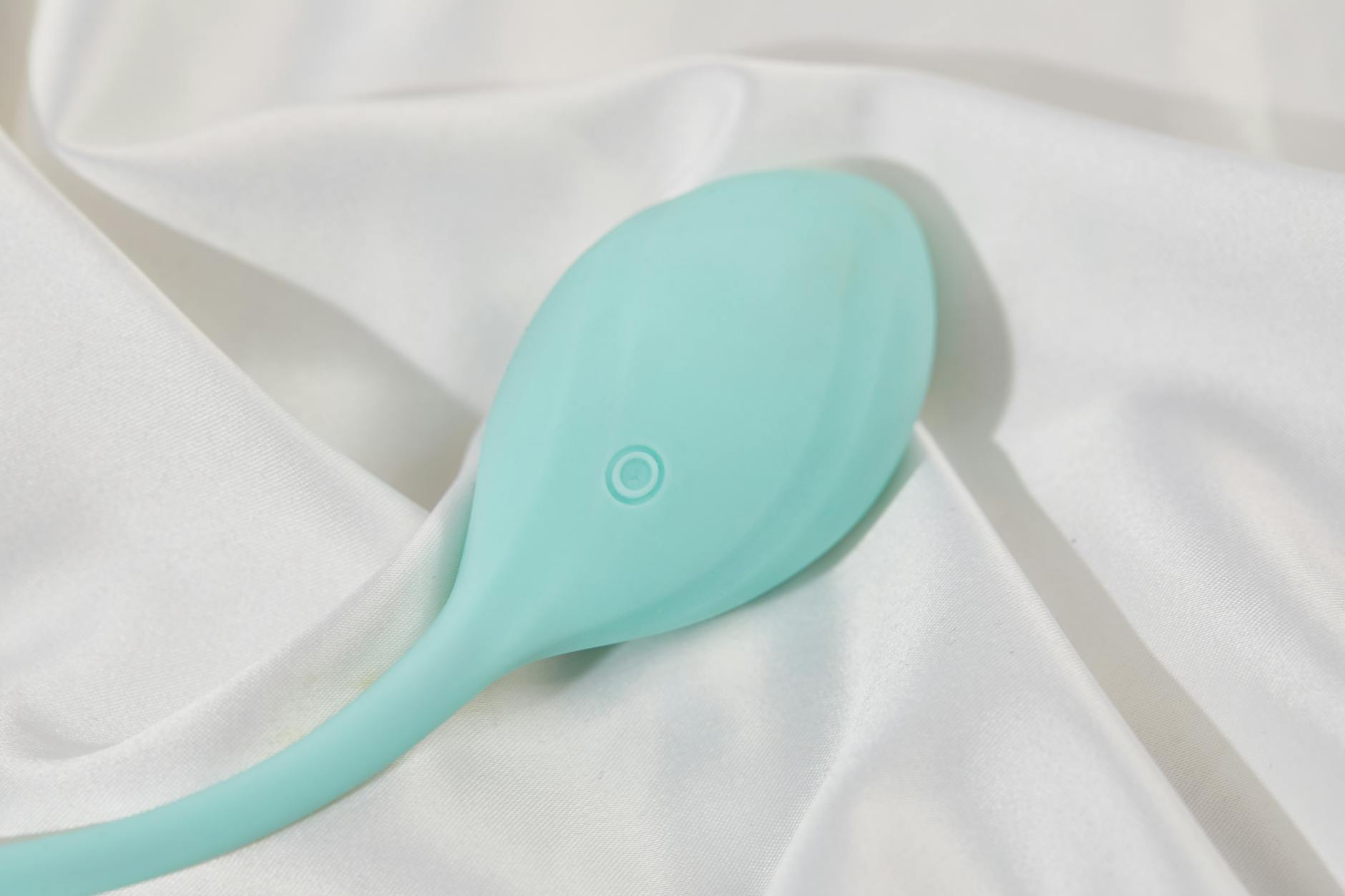 A sleek lemon clitoral vibrator resting on soft white silk, symbolizing sensuality and comfort after menopause