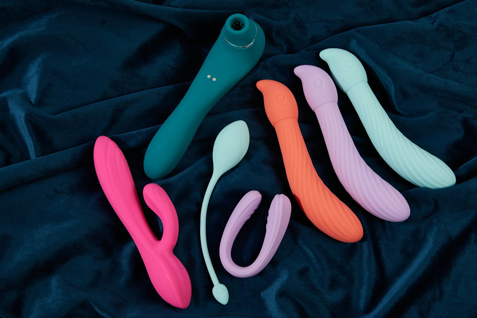 Colorful silicone clitoral vibrators arranged on dark blue fabric