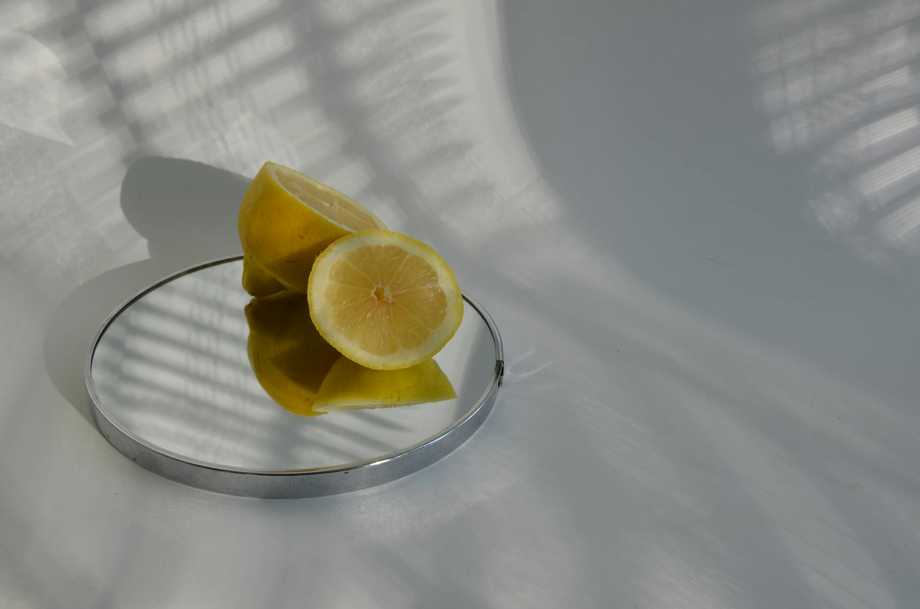 Sliced lemons on a reflective surface casting shadows, symbolizing clarity and intentional timing.
