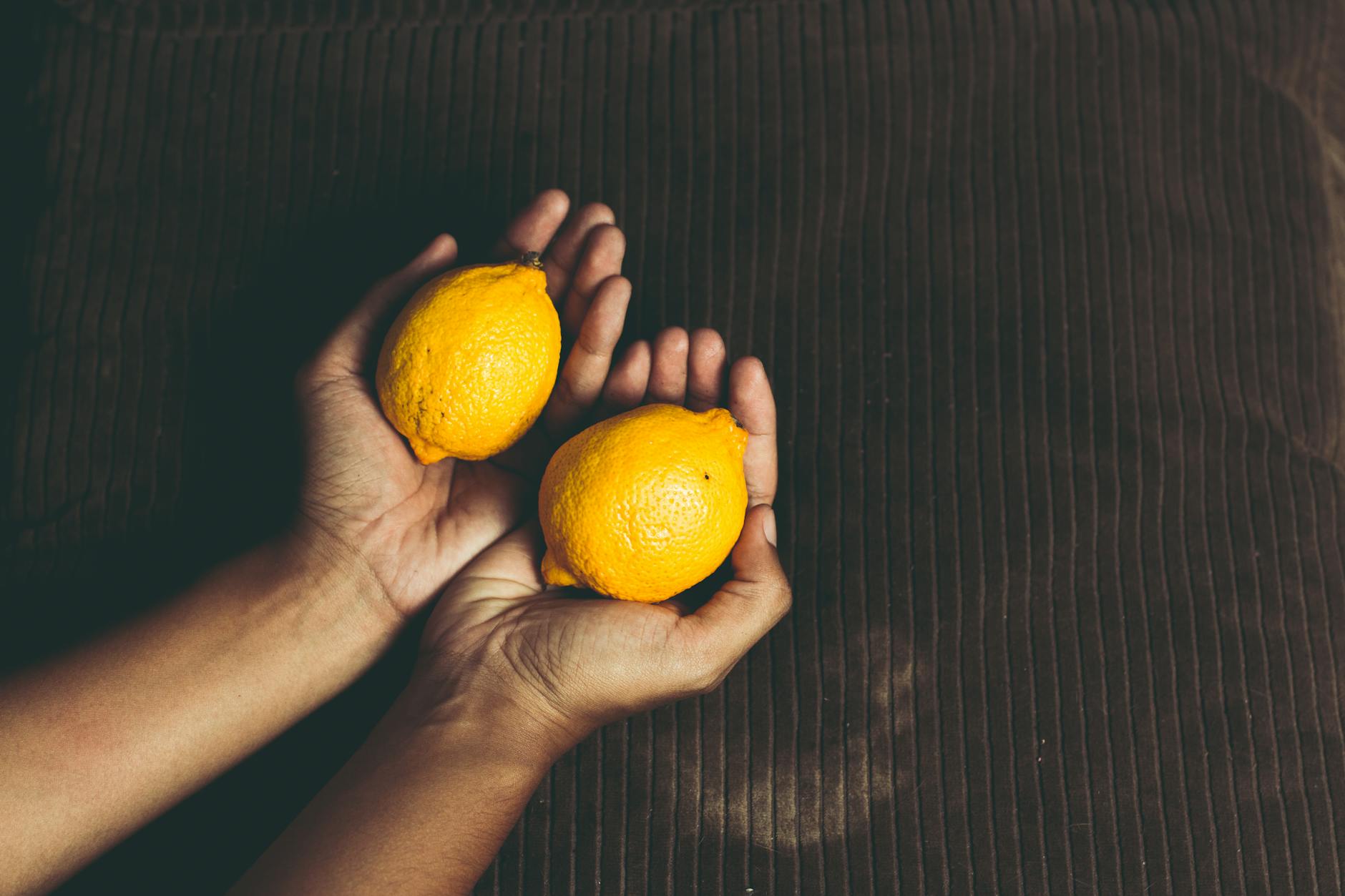 A hand holding a fresh lemon against a vivid yellow background, symbolizing clarity and personal wellness.
