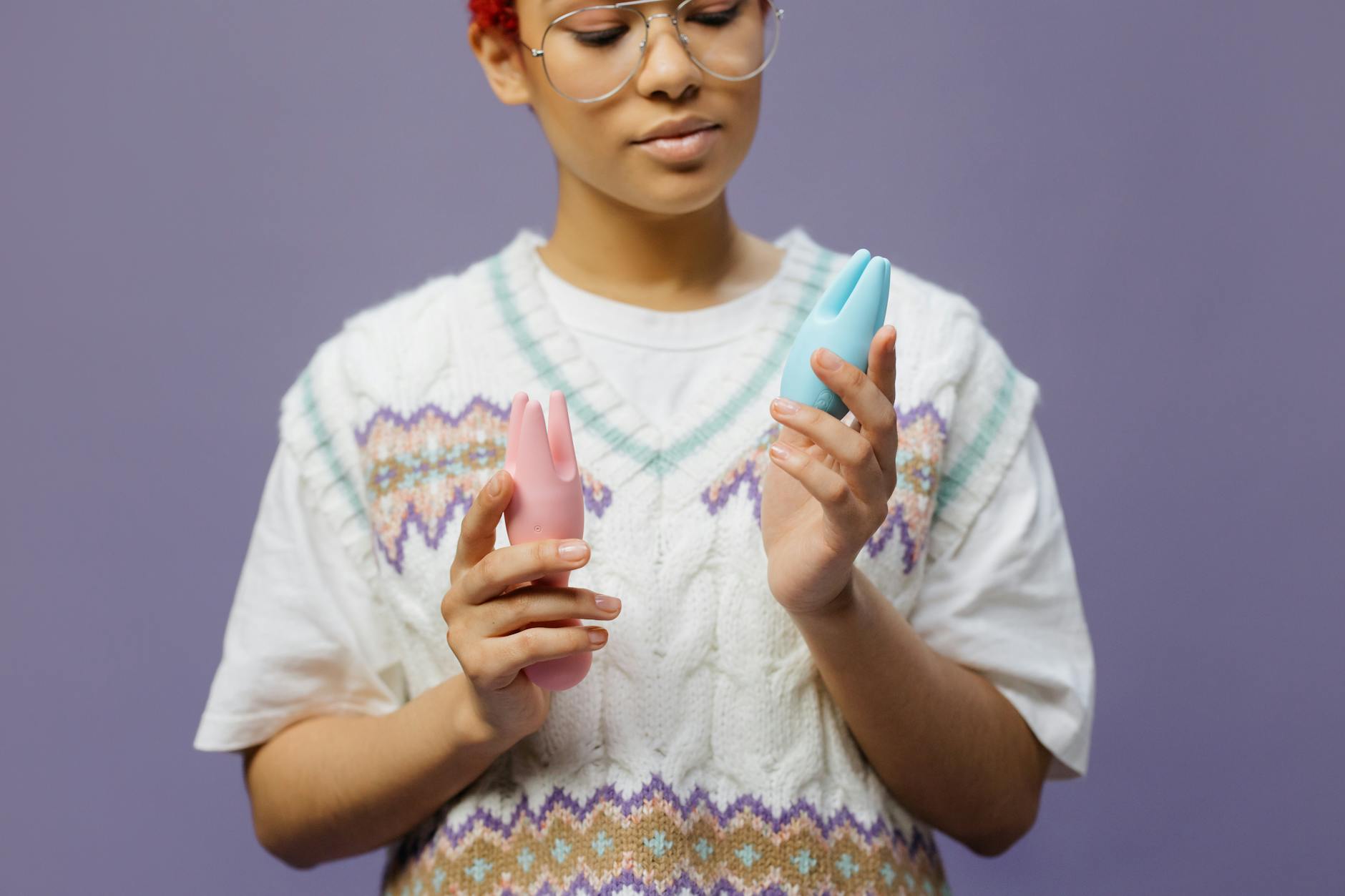 Woman holding vibrators with a thoughtful expression, representing mature sexuality and pleasure exploration
