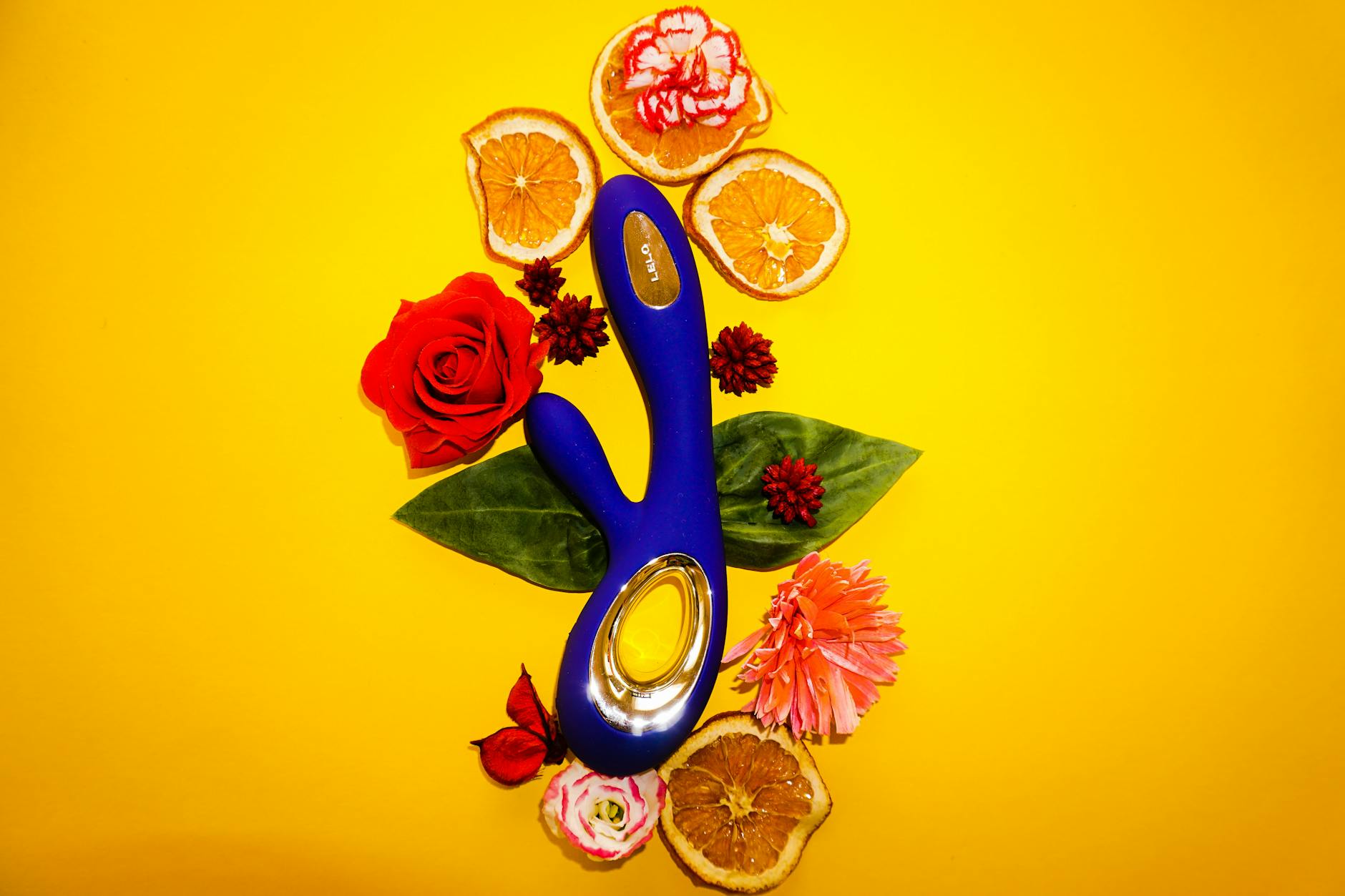 Blue lemon vibrator surrounded by flowers and citrus on a bright yellow background