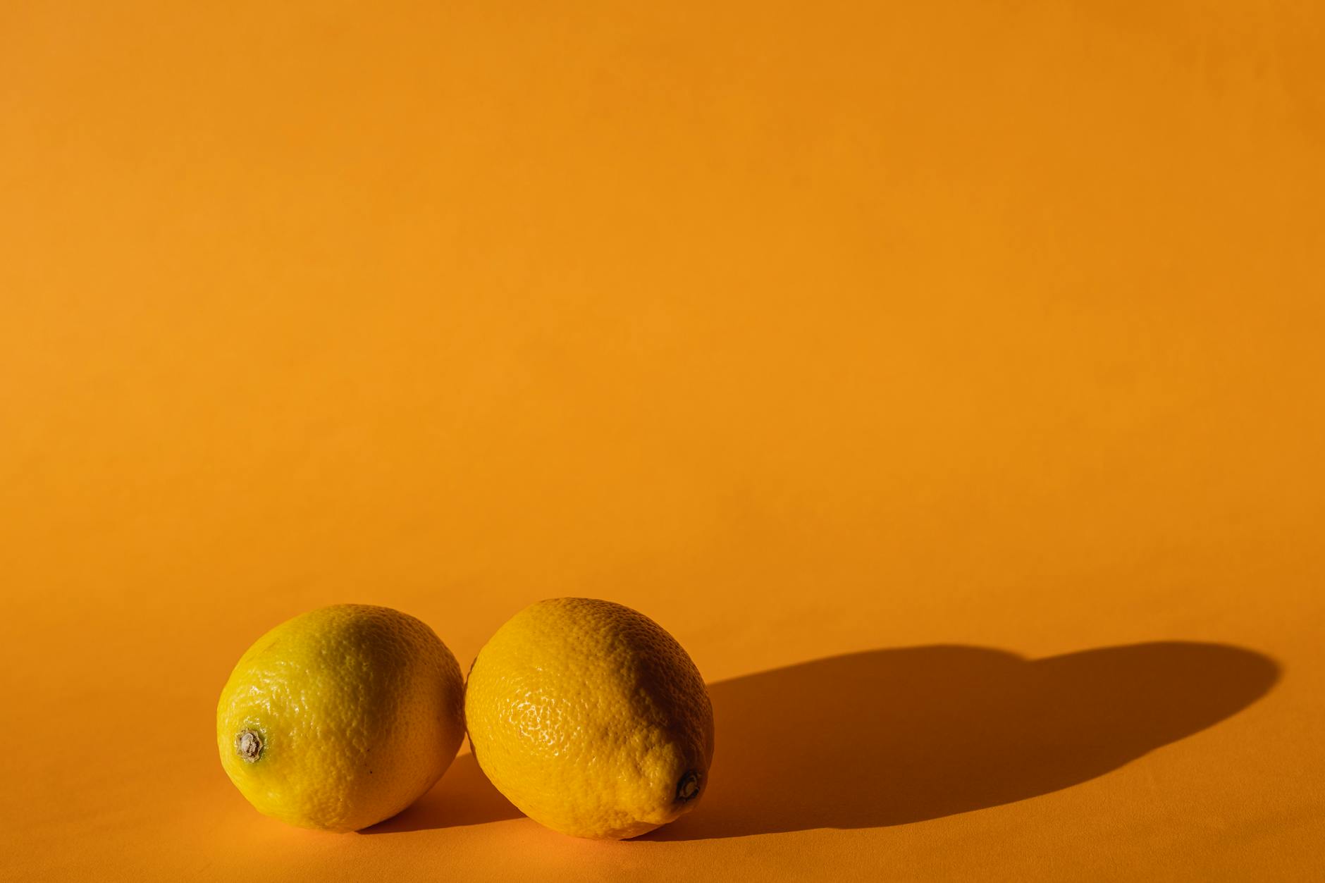 Ripe vivid lemons composed on yellow background of modern studio in bright daylight